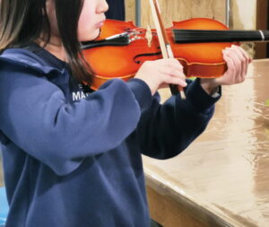 バイオリンの弾き方を練習する小学生