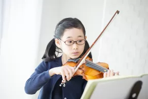 楽譜をみながらバイオリンを練習する子ども