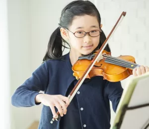 楽譜をみながらバイオリンを練習する子ども