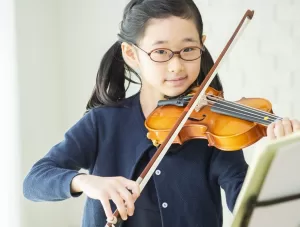 楽譜をみながらバイオリンを練習する子ども