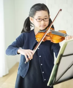 楽譜をみながらバイオリンを練習する子ども