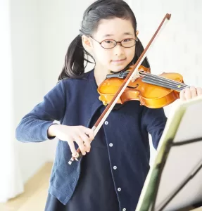 楽譜をみながらバイオリンを練習する子ども